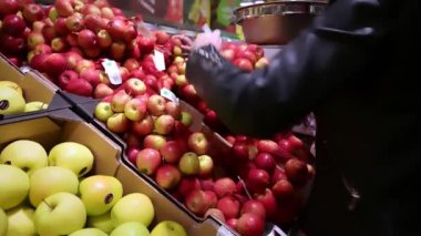 Çantası olan kadın bakkaldan elma alıyor. Tüketim ve insanlar