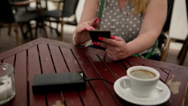 一名妇女坐在室外咖啡店时 从外部电池充电 旅行收费小工具的概念 — 图库视频影像