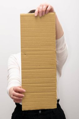 The hand is holding an empty cardboard sign. Copy space for text on cardboard. A woman is holding a sign on a white background.
