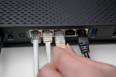 Woman's hand connects internet cable to LAN wired network switch. Internet communication and computer technology concept.