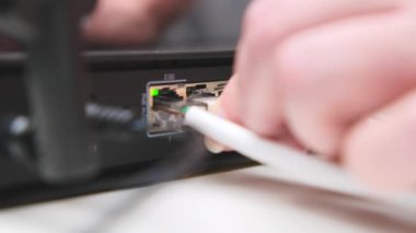 Woman's hand connects internet cable to LAN wired network switch. Internet communication and computer technology concept.