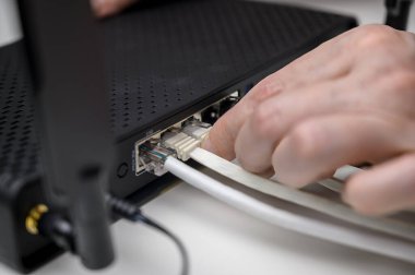 A woman's hand connects an internet cable to a router socket. Fast and wireless internet concept