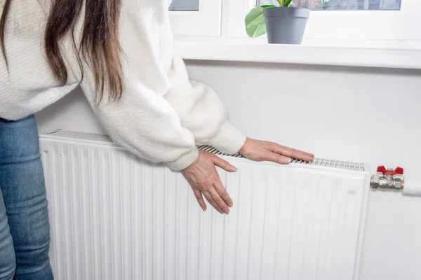 a woman warms her hands over a heater. Warm and cozy home on cold winter days.