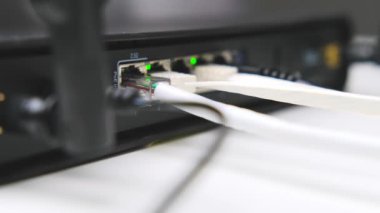 Yönlendiriciye bağlı bir kabloya yakın çekim. Ethernet yönlendiricisinde yanıp sönen yeşil LED 'ler.
