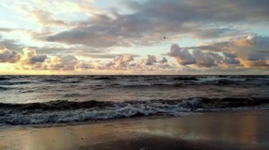 Sahile dalgaların geldiği bir sahil. Sabahın köründe deniz manzarası, denizin üzerinde gün doğumu..
