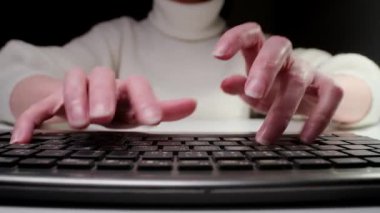 Ev ofisinde çalışan bir kadın, elleri bilgisayar klavyesinde daktilo eden yakın plan.
