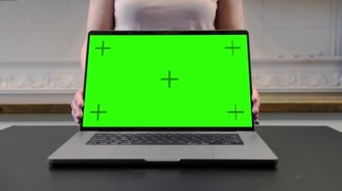 Kadın boş yeşil bir ekranla dizüstü bilgisayarı çeviriyor. Ekran Modeli.