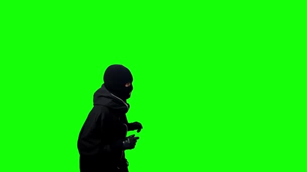 コンセプトをキャッチ 黒いバラクラバと手袋をした泥棒が緑の背景に隔離された手を上げて — ストック動画