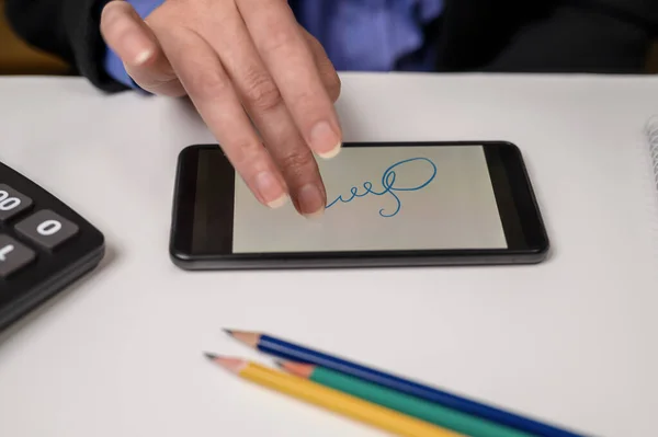 Digital signature on smartphone screen with woman hand. a close up of a person writing on a cell phone.