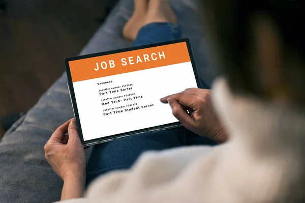 Woman browsing job opportunities online using tablet application for job search. unemployed job seeker looking for new vacancies on website page on tablet screen, hiring concept, rear view