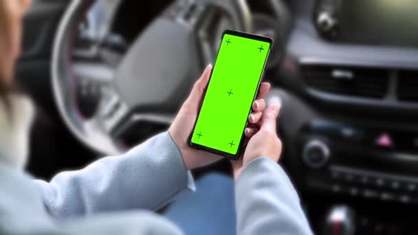 空白の画面で女性の手を保持スマートフォンのクローズアップ 車のステアリングホイールの背景 モックアップ — ストック動画