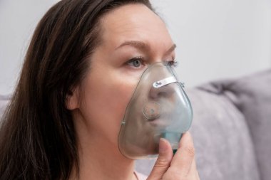 Hasta kadın oksijen maskesi kullanarak solunum yapıyor. Sağlıksız kız ciddi viral hastalıktan muzdarip..