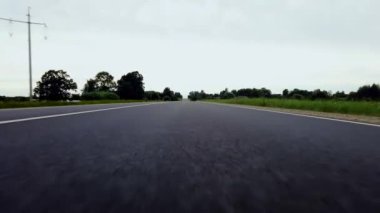 Düşük açılı bir yol ve mavi gökyüzü ve bulutlu yeşil tepeler. Bakış açısında yol.