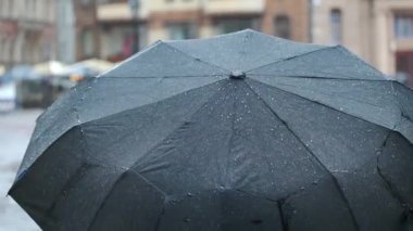 Siyah şemsiyeli bir kadın yağmurlu havada şehirde yürür..