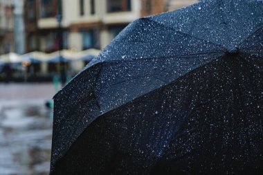 Yağmurda siyah şemsiye. Şemsiyenin tüm yüzeyi yağmur damlalarıyla kaplı.