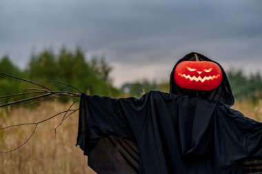 Kalın bulutların arkasında, sahada korkunç bir korkuluk. Cadılar Bayramı konsepti