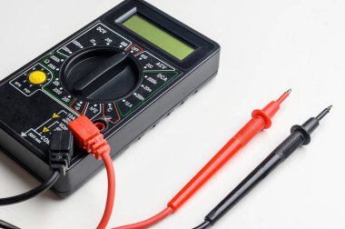 Beyaz bir masada test ipuçlarıyla dijital çokölçer. Çoklu metre elektronik bir ölçüm aletidir..