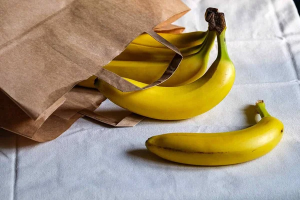 bananas in a paper bag lie on the table. bananas in the kitchen.