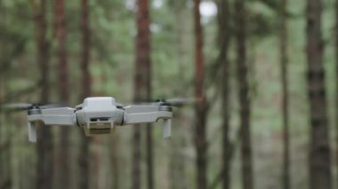 Modern bir dron ormanda uçar. Bir orman manzarasına karşı havada küçük bir dron..