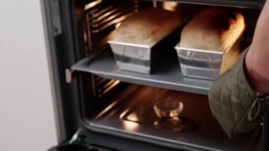 Aşçı sıcak fırından fırında pişmiş ekmeği çıkarır. Aşçı fırında ekmek pişirir..