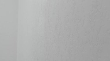 Tamirci yakın çekim, el işi ve yenileme konsepti kullanarak bir apartmanın duvarını beyaza boyuyor.