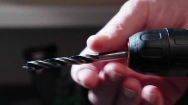 Usta elektrikli sondaj makinesine matkap takıyor. DIY onarımları.