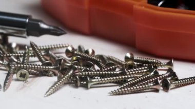 Tahta bir masada tornavida ve enjektör setinin arka planına karşı vidalar. vida yakın çekim.