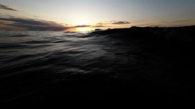 Gün batımında dalgalanan su yüzeyi, dalgalar yakın, alçak açı
