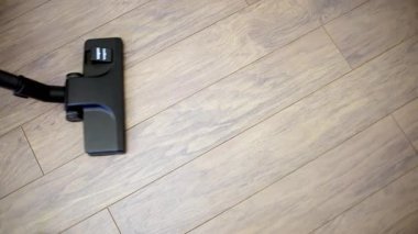 Elektrik süpürgesinin kafasının hafif ahşap kaplama döşeme, temizlik ve düzenli bakım konularını vurguluyor..