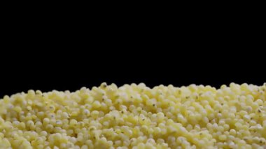 Sarı darı taneciklerinin yakın plan görüntüsü yoğun bir şekilde siyah arkaplan üzerine yığılmış.