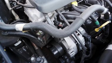 Modern bir araba motoru kompartımanına yakın çekim. Detaylı mekanik bileşenler ve gündüz kabloları sergileniyor.
