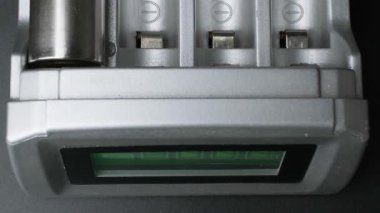 Modern şarj edilebilir pillerin yakın çekim görüntüsü. Kapalı mekanda dijital ekran ile donatılmış gösterişli bir elektronik pille şarj ediliyor.
