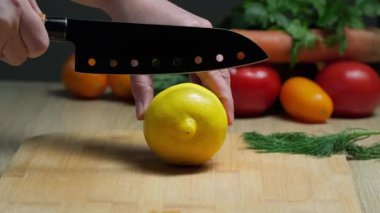 Mutfakta renkli sebzelerle ahşap kesim tahtasında El Dilimleme Taze Limonu 'nun yakın çekimi