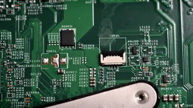 Çeşitli mikroçipleri ve elektronik bileşenleri gösteren, karmaşık elektronik devreleri gösteren yeşil devre kartının ayrıntılı görüntüsü.