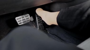 Modern aracın içinde iş kadını ayağının siyah topuklu gaza basma pedalı.