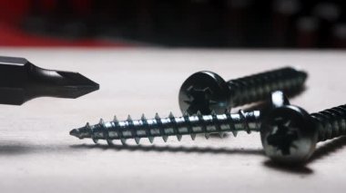 Atölye ortamında tornavida ısırığının yakın görüntüsü ve ahşap yüzey üzerindeki parlak metal vidalar