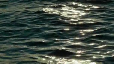 Okyanus yüzeyinde Ilık Günbatımı Işığı Altında Parlayan Deniz Dalgalarının Soyut Yakın Çekimi