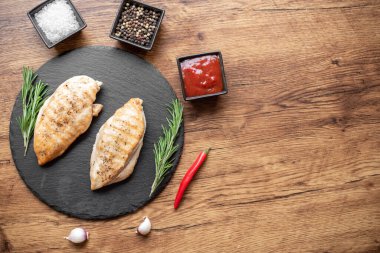 grilled chicken fillet with spices and herbs on wooden background