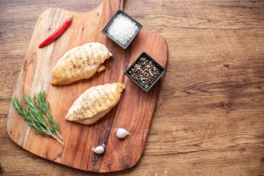 grilled chicken fillet with spices and herbs on wooden background