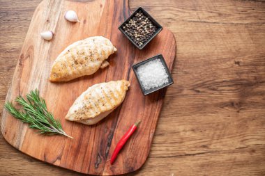 grilled chicken fillet with spices and herbs on wooden background