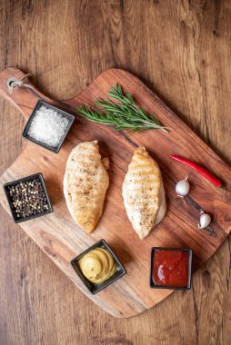 grilled chicken fillet with spices and herbs on wooden background