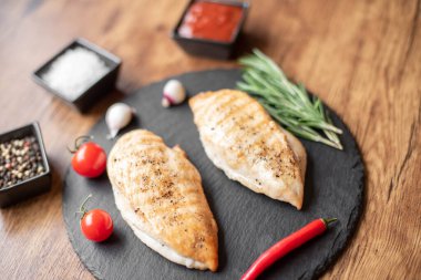 grilled chicken fillet with spices and herbs on wooden background