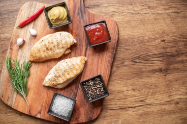grilled chicken fillet with spices and herbs on wooden background