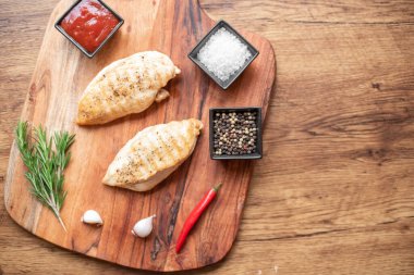 grilled chicken fillet with spices and herbs on wooden background