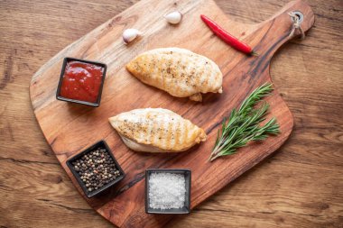 grilled chicken fillet with spices and herbs on wooden background