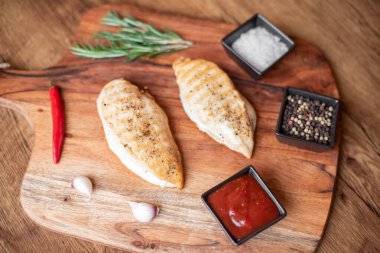 grilled chicken fillet with spices and herbs on wooden background