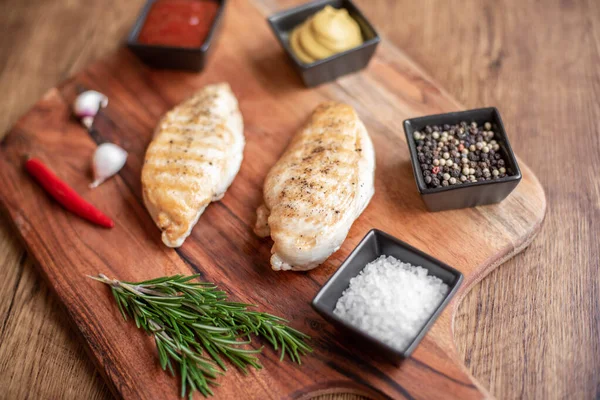 grilled chicken fillet with spices and herbs on wooden background