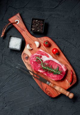 Siyah arka planda baharatlı ve otlu çiğ biftek. en üstteki görünüm