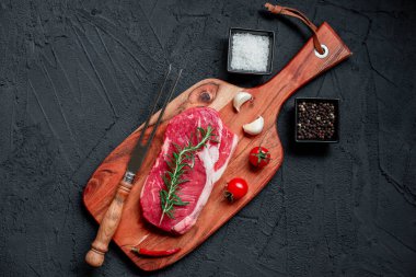 Siyah arka planda baharatlı ve otlu çiğ biftek. en üstteki görünüm