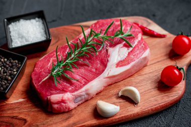 Siyah arka planda baharatlı ve otlu çiğ biftek. en üstteki görünüm